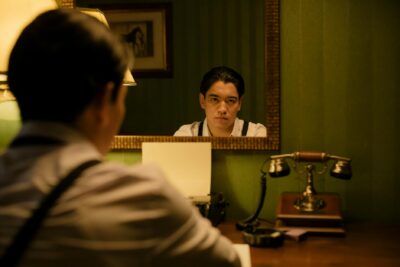 A vintage scene of a man reflecting in a mirror beside a classic telephone, creating a nostalgic atmosphere.