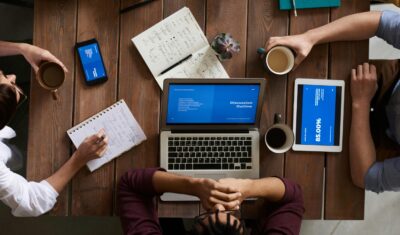 top view. Group of coworkers discussing business strategies with laptops and tablets in a modern office setting. Team Productivity