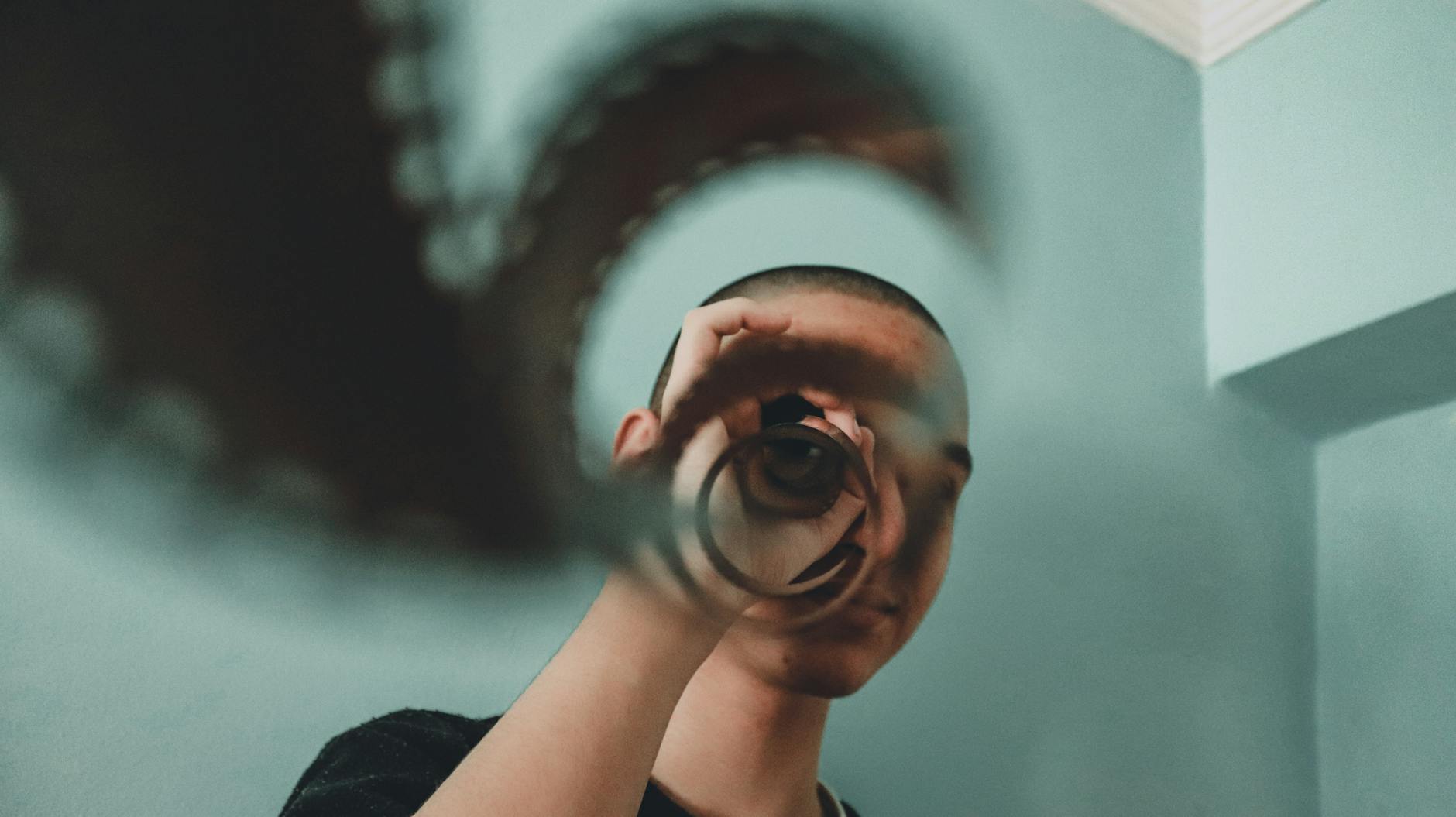Artistic portrait of a person indoors using a vintage film reel for reflection and visual effect. Self-Reflection