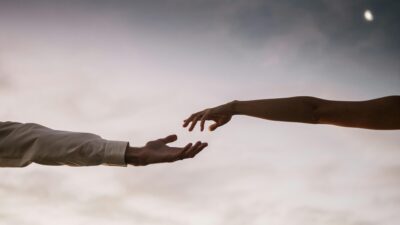 Two hands reaching towards each other against a soft twilight sky symbolizing connection and love. empathy brain connection