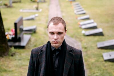 Emotional resilience.A somber man dressed in black standing in a cemetery,